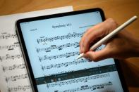 Un miembro de la orquesta Nexus anota una partitura en una tableta durante un ensayo en Lausana, Suiza, el 2 de septiembre de 2021 (AFP/Fabrice Coffrini)