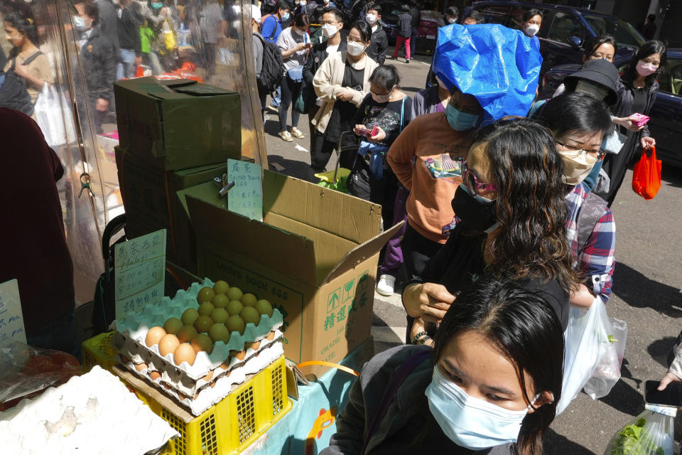 FILE - People wearing face masks queue up to buy vegetables as residents worry about a shortage of fresh food, at a market in Hong Kong on March 1, 2022. The fast-spreading omicron variant is overwhelming Hong Kong, prompting mass testing, quarantines, supermarket panic-buying and a shortage of hospital beds. Even the morgues are overflowing, forcing authorities to store bodies in refrigerated shipping containers. (AP Photo/Vincent Yu, File)