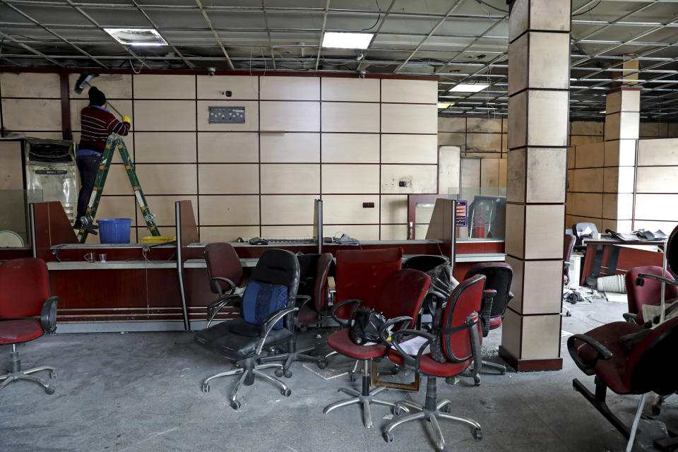 A worker cleans the walls of a bank that was attacked during protests over rises in government-set gasoline prices, in Tehran, Iran, Wednesday, Nov. 20, 2019. Demonstrations struck at least 100 cities and towns, spiraling into violence that saw banks, stores and police stations attacked and burned. (AP Photo/Ebrahim Noroozi)