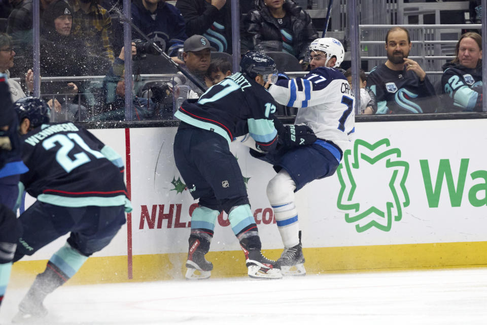 Seattle Kraken center Jaden Schwartz (17) collides with Winnipeg Jets defenseman Kyle Capobianco (77) while they battle for the puck during the first period of an NHL hockey game, Sunday, Dec. 18, 2022, in Seattle. (AP Photo/John Froschauer)