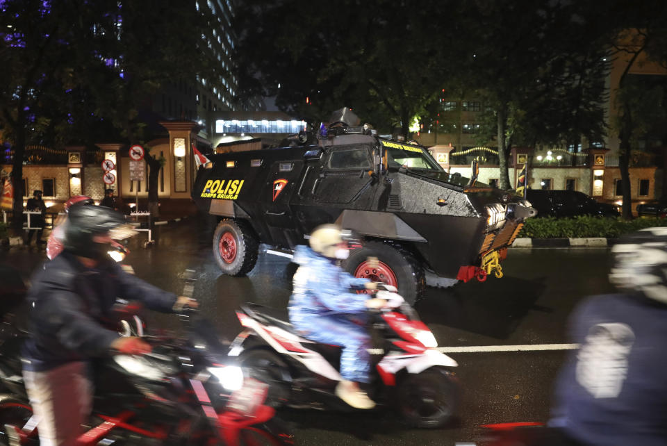 Motorists ride past a police armored vehicle parked outside the National Police Headquarters following a suspected militant attack in Jakarta, Indonesia, Wednesday, March 31, 2021. A woman entered the Indonesian National Police Headquarters in Jakarta and pointed a gun at several officers before being shot dead by police, in the latest in a series of militant attacks in the world's most populous Muslim nation. (AP Photo/Dita Alangkara)