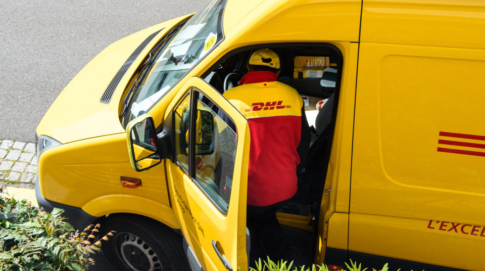 Paris, France - April 21, 2016: Courier enters DHL yellow delivery van after delivering the on time delivering package parcel