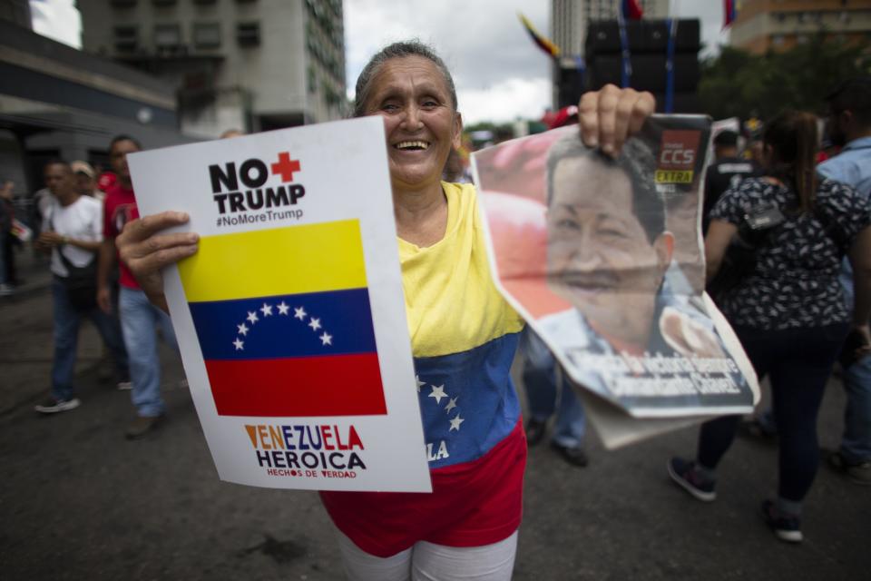 A supporter of President Nicolas Maduro holds on her left hand a poster that in Spanish reads "No more Trump" and on her right an image of Late President Hugo Chavez, during an anti-imperialist rally in Caracas, Venezuela, Saturday, August 31, 2019. Venezuelan officials say they have proof of paramilitary training camps operating in neighboring Colombia where groups are purportedly plotting attacks to undermine President Nicolás Maduro. (AP Photo/Ariana Cubillos)