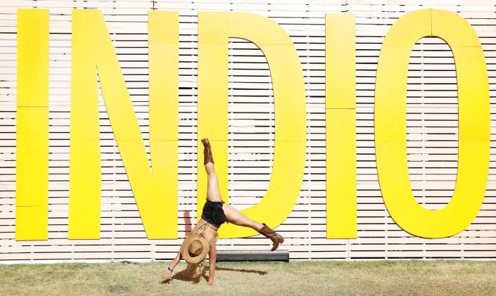 A woman does a cartwheel in front of a yellow sign that says &quot;Indio&quot;
