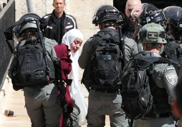 Israeli security members detain a Palestinian woman at Damascus Gate just outside Jerusalem's Old City during a demonstration held by Palestinians to show solidarity amid Israel-Hamas fighting.