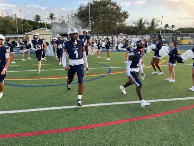 American Heritage players charge onto the field before Friday night's homecoming game against Archbishop McCarthy in Delray Beach.