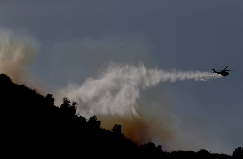 NEWHALL, CA. - JAN. 19, 2021. A firefighting helicopter makes a water drop on a brush fire in the hills above Ed Davis Park in Newhall on Tuesday, Jan. 19, 2021. (Luis Sinco/Los Angeles Times)