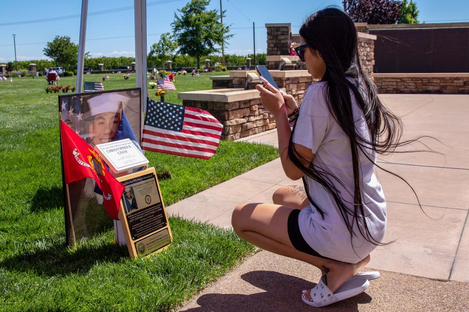 Jade Lot, of Stockton, takes a photo of the plaque for her bother, Christopher Gnem, at the Memorial Day service Monday, May 30, 2022, at Cherokee Memorial Park and Funeral Home in Lodi.