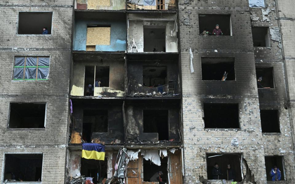 Local residents clear debris from apartments at a heavily damaged residential building, three days after a Russian missile attack in Kyiv