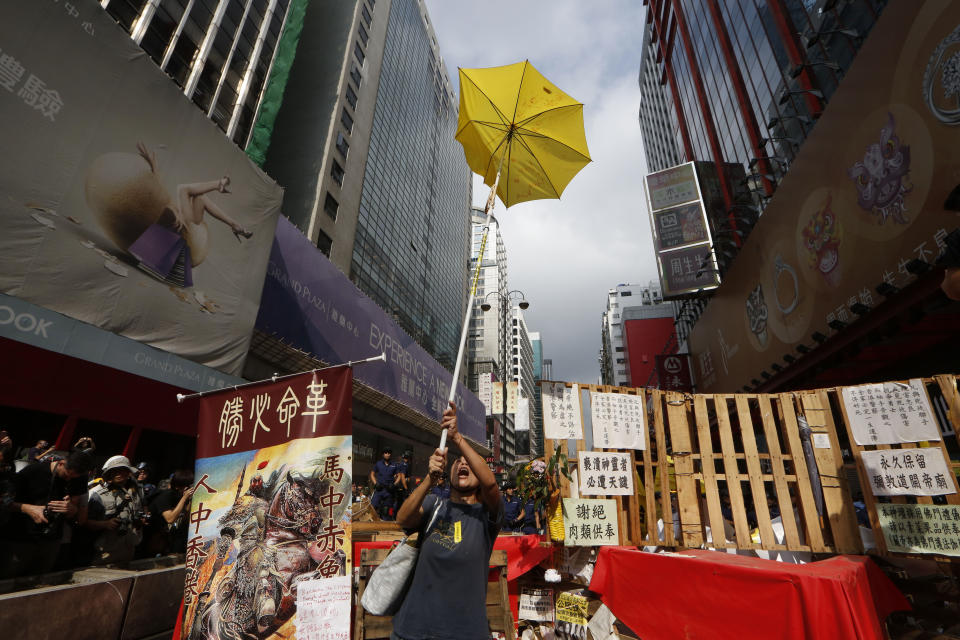 FILE - In this file photo taken Wednesday, Nov. 26, 2014, a protester holds a yellow umbrella, the symbol of Hong Kong's pro-democracy movement, at the barricades as the police keep clearing them away at an occupied area in Mong Kok district of Hong Kong. A legislative bill that harkened back on Beijing's promise to allow Hong Kong residents to vote for their leader, triggered massive demonstrations in Hong Kong's most crowded districts, led by young activists and lasting 79 days. The movement's organizers called it "Occupy Central with Love and Peace," but around the world, the sustained sit-in came to be known as the "Umbrella Revolution" for the yellow umbrellas which protesters used as shields against police pepper spray. (AP Photo/Kin Cheung)