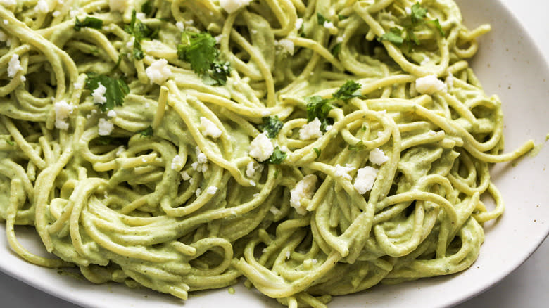 spaghetti with green sauce on ceramic plate