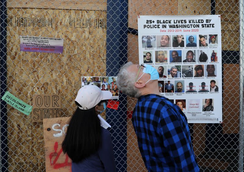 Protesters stand in front of poster during a protest against racial inequality and call for defunding of Seattle police, in Seattle