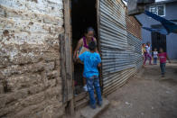 A resident picks up a box with food given to them by the army at the Santa Rosita neighborhood on the outskirts of Guatemala City, Monday, April 6, 2020, during a stay-at-home curfew designed to slow the spread of the new coronavirus. (AP Photo/Moises Castillo)