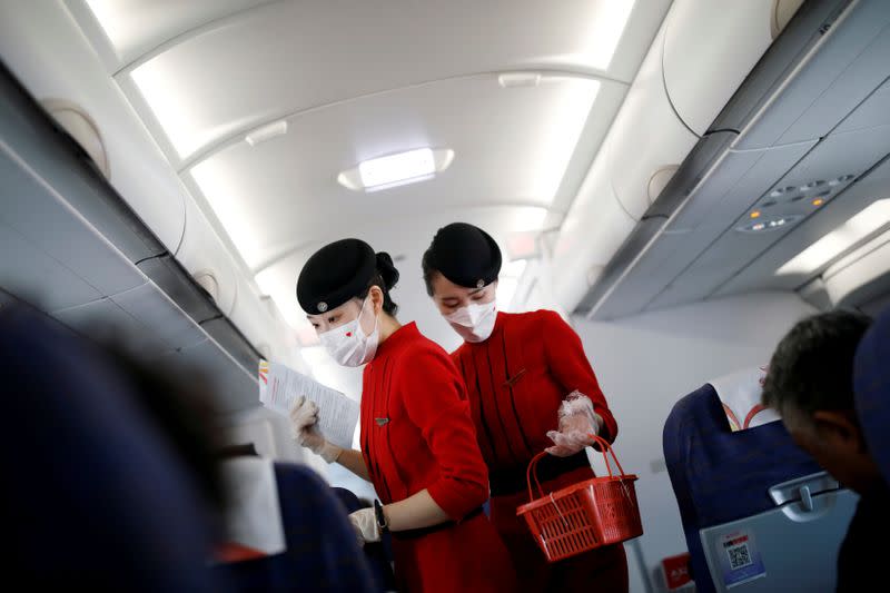 FILE PHOTO: Flight attendants wearing face masks and gloves following the coronavirus disease (COVID-19) outbreak are seen inside a Sichuan Airlines aircraft before the flight takes off from Xichang Qingshan Airport in Xichang