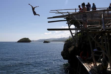 A tourist jumps off a 20-feet cliff at one of the islets off the island of Boracay, central Philippines January 18, 2016. REUTERS/Charlie Saceda/Files