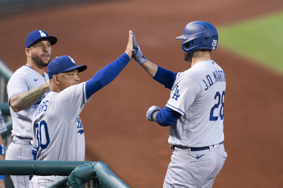 Los Angeles Dodgers designated hitter J.D. Martinez, right, celebrates with manager Dave Roberts, front left, after hitting a two-run home run during the first inning of a baseball game against the Washington Nationals, Friday, Sept. 8, 2023, in Washington. (AP Photo/Stephanie Scarbrough)