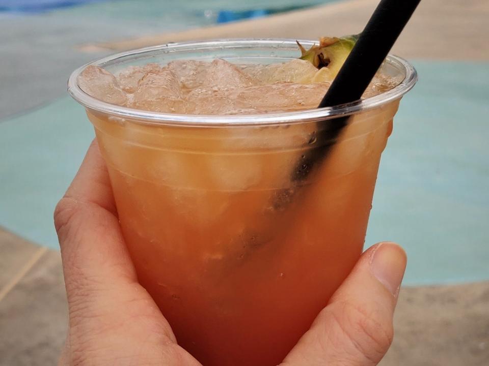hand holding up a cocktail at the big blue pool at disney's art of animation resort
