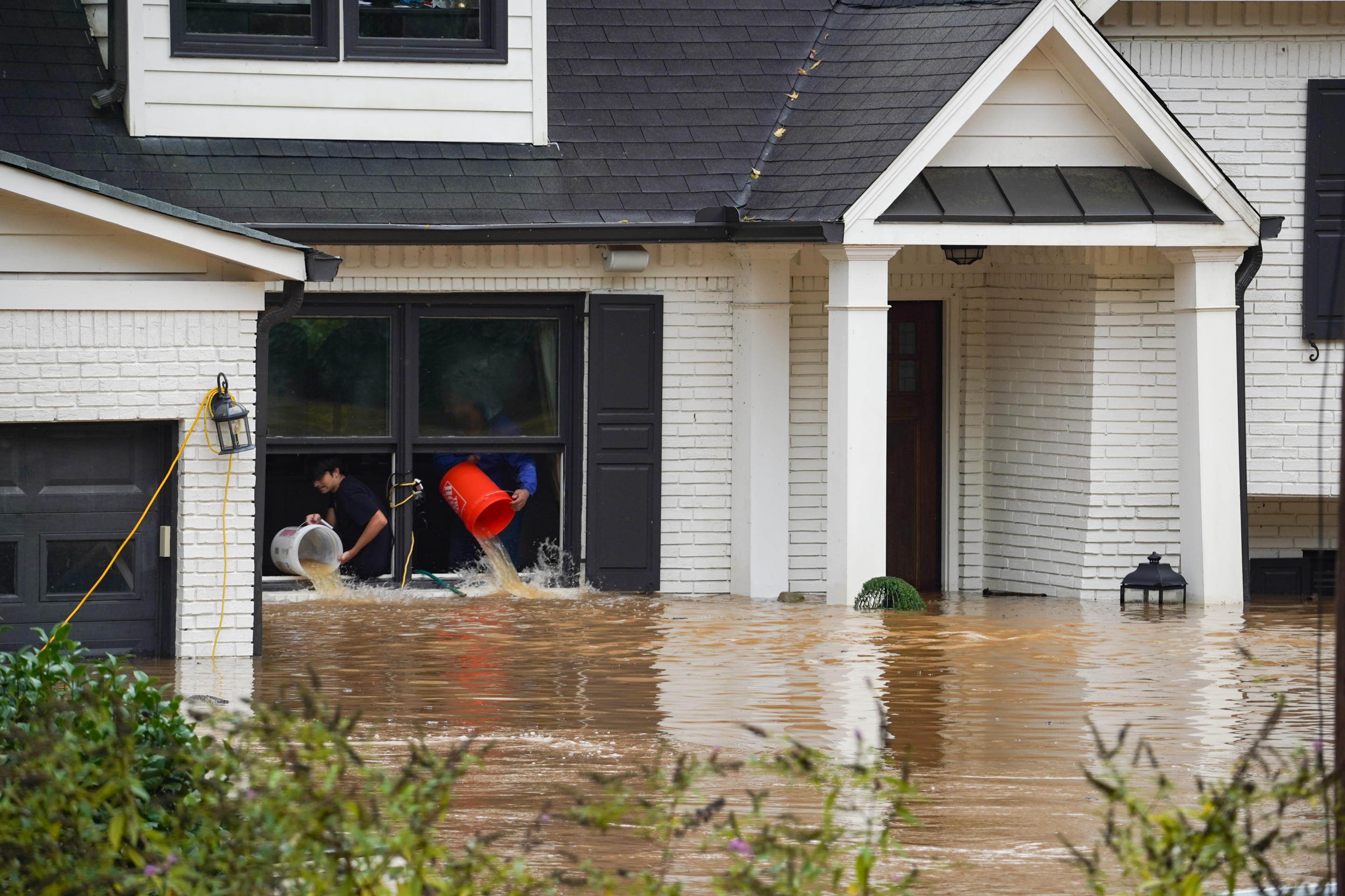 People throw buckets of water from a home as streets and homes are flooded near Peachtree Creek after Hurricane Helene brought heavy rains to Atlanta, Georgia, on Friday. (Megan Varner/Getty Images)