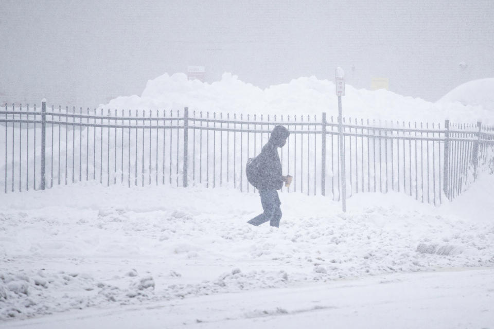 A person walks through downtown in the snow Friday, Nov. 18, 2022, in Buffalo, N.Y. A dangerous lake-effect snowstorm paralyzed parts of western and northern New York, with nearly 2 feet of snow already on the ground in some places and possibly much more on the way. (AP Photo/Joshua Bessex)