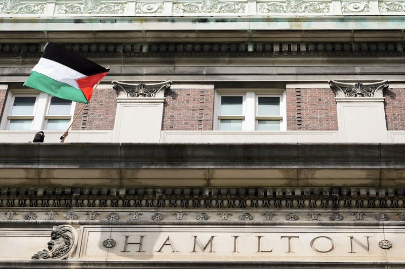 A protester waves a Palestinian flag Tuesday from Hamilton Hall at Columbia University in New York City. Students protesting the war in Gaza have barricaded themselves in the building, as the university warned they will face expulsion as students were warned to stay away from campus. Pool Photo by Mary Altaffer/UPI