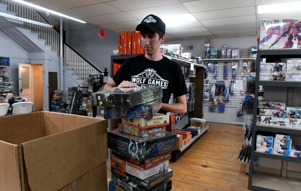 Mike Wolfe, co-owner of Wolf Games & Models in downtown Massillon, stocks shelves at the store.