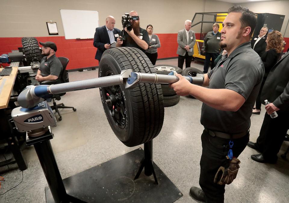 Josh Harper, a technician at Kenda Tires American Technology Center in Green, demonstrates equipment used to take 3-dimensional measurements of a tire during a tour of the facility.