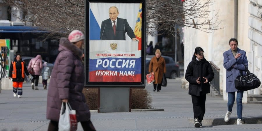 Pedestrians walk past a poster in support of Russian dictator Vladimir Putin in Sevastopol, Occupied Crimea