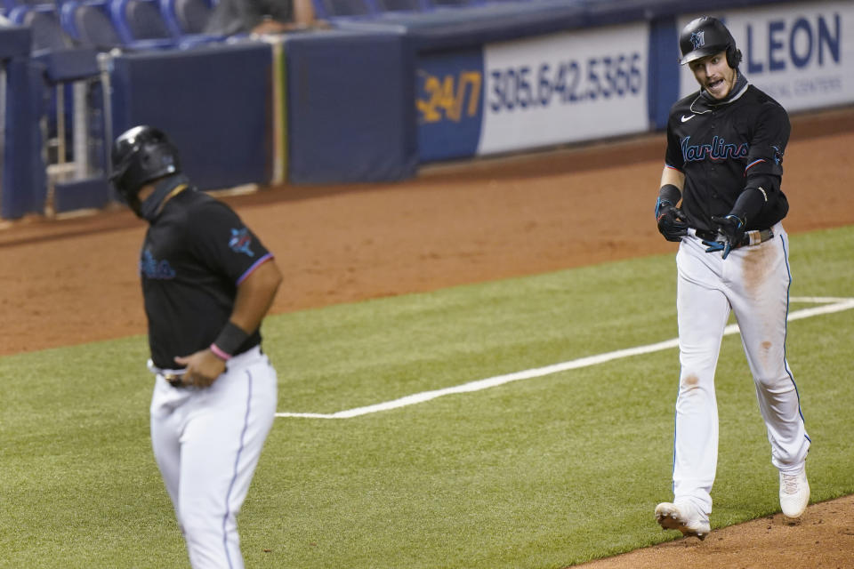 Miami Marlins' Brian Anderson, right, gestures to Jesus Aguilar as Aguilar waits for him to cross home plate after he hit a home run also scoring Aguilar and Garrett Cooper during the fifth inning of the second game of a baseball doubleheader against the Washington Nationals, Friday, Sept. 18, 2020, in Miami. (AP Photo/Wilfredo Lee)