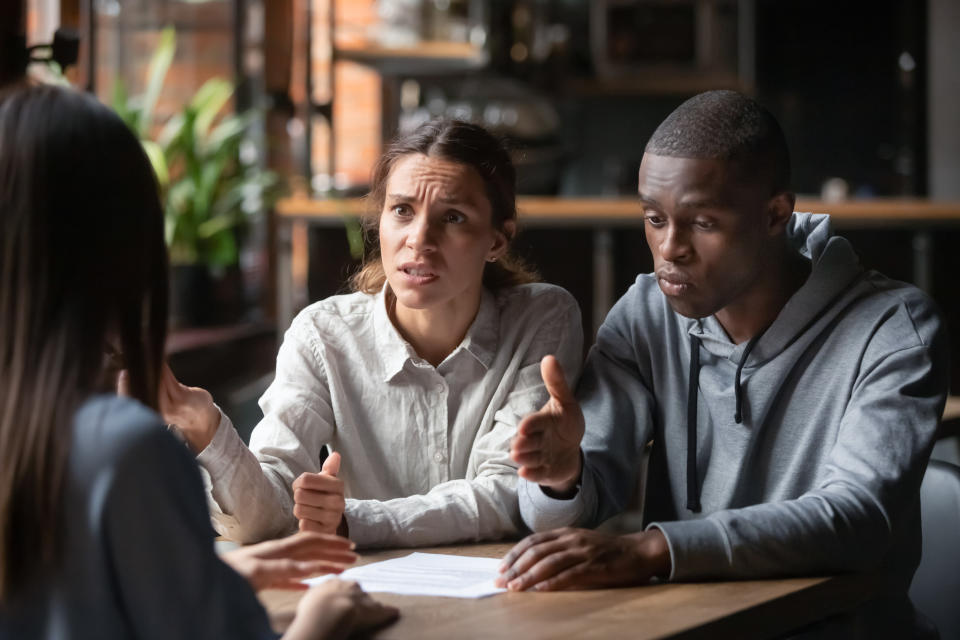 Two people sitting across from another at a table and talking