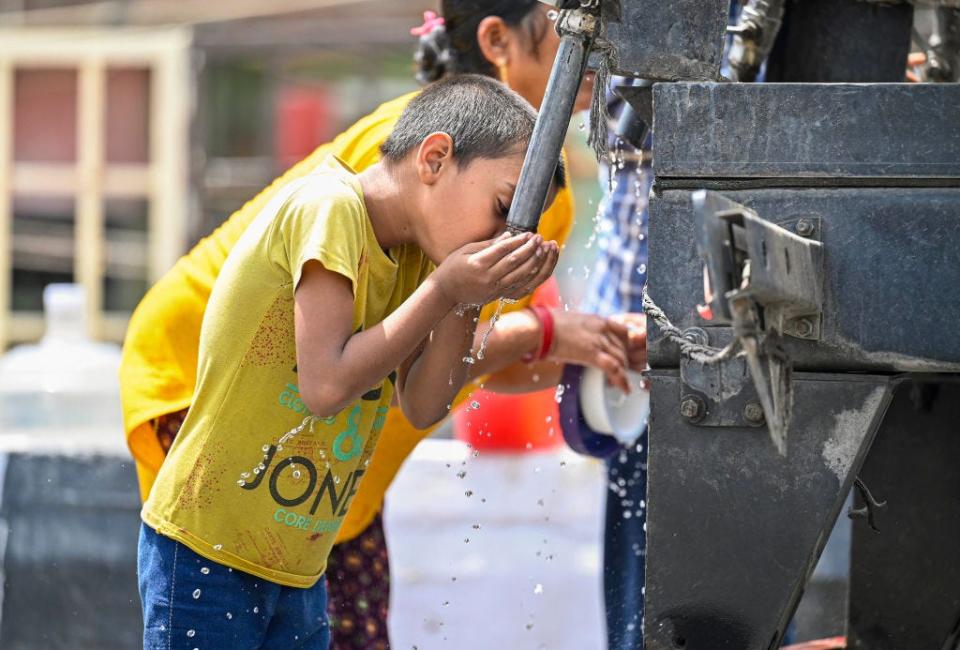 A boy quenching his thirst from water tank tap from scorching heat waves, on May 30, 2024 in New Delhi, India.