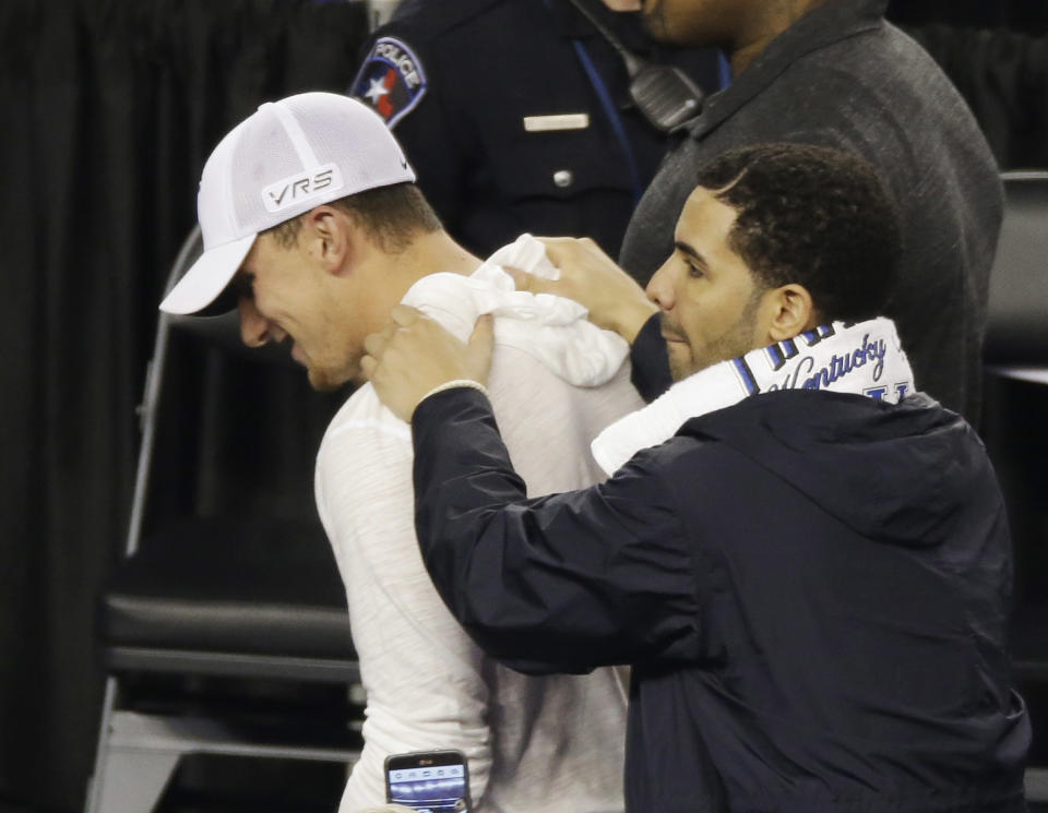 Former Texas A&M football quarterback Johnny Manziel, left and entertainer, Drake leave the floor during halftime of the NCAA Final Four tournament college basketball semifinal game between Wisconsin and Kentucky Saturday, April 5, 2014, in Arlington, Texas. (AP Photo/David J. Phillip)