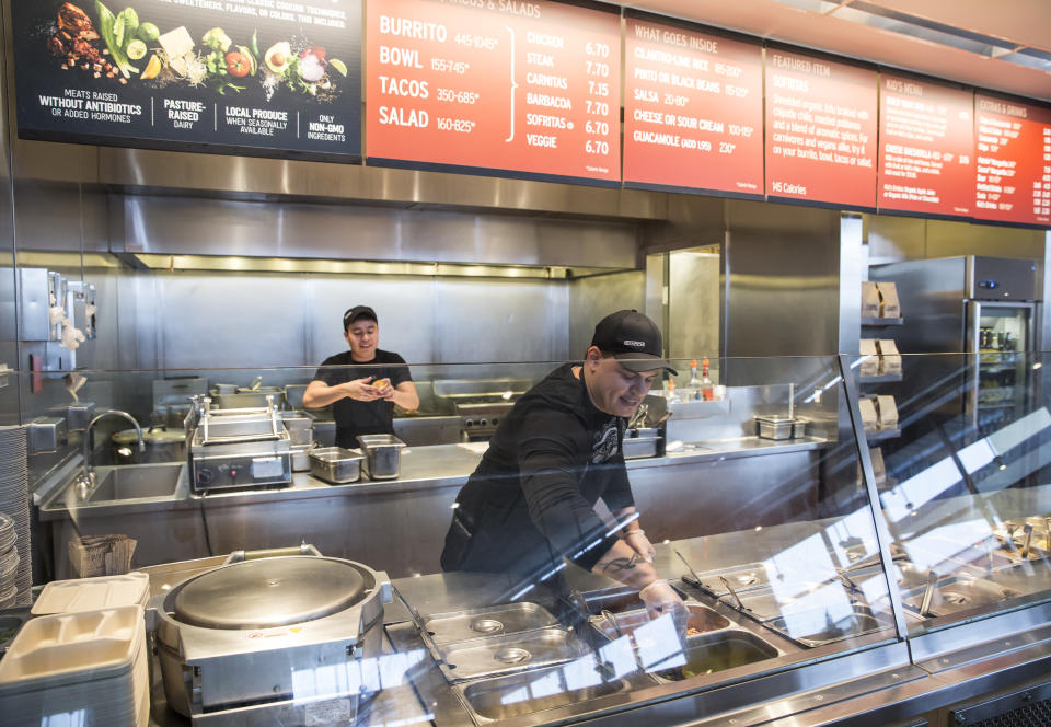 A Chipotle Mexican Grill employee prepares food on Tuesday, Dec. 15, 2015, in Seattle.  Steve Ells, founder and CEO of Chipotle, visited restaurants in the Pacific to discuss new food safety protocols with employees after an E. coli outbreak sickened 50 people in the Northwest.  (AP Photo/Stephen Brashear)