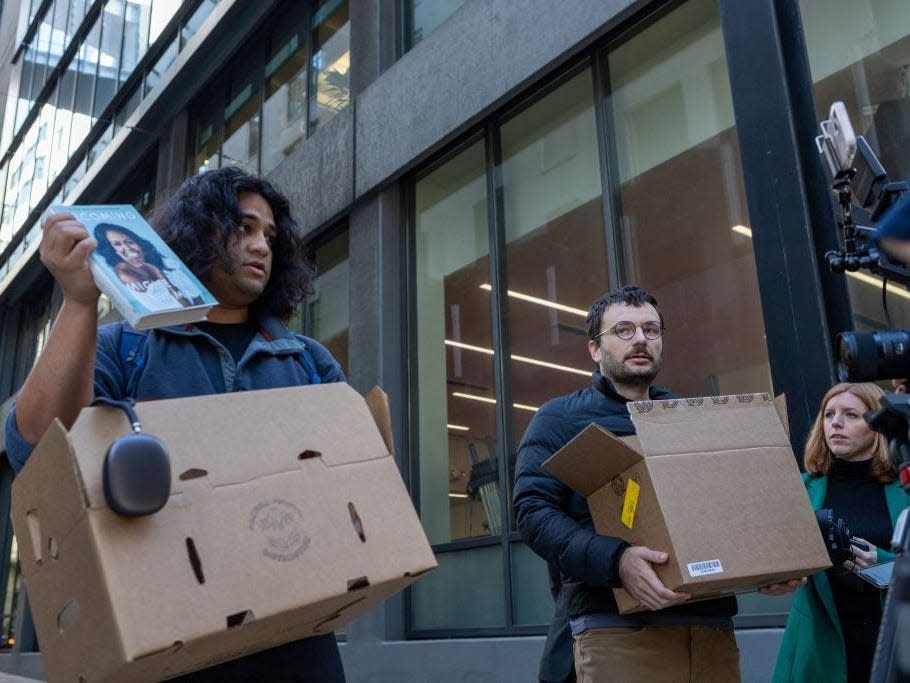 Two people who claim to be Twitter employees, speak with reporters outside Twitter headquarters on October 28, 2022, in San Francisco, California. It later emerged that they were likely practical jokers pretending to be laid off Twitter staff.