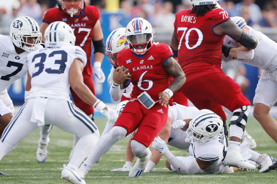 Kansas quarterback Jalon Daniels (6) attempts to get past BYU's Kamden Garrett (7) and Raider Damuni (33) as he scrambles for a first down during the third quarter of a game this year on Sept. 23 in Lawrence.