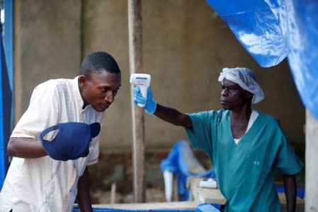 FILE PHOTO: A health worker measures the temperature of a man entering the ALIMA Ebola treatment centre in Beni