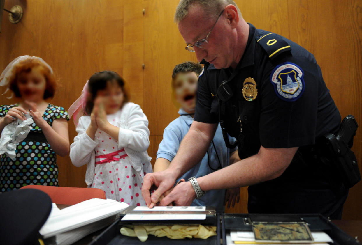 FILE -- Several children gets fingerprinted by Capitol Police Officer Howard Liebengood on April 24, 2008. / Credit: Tom Williams/Roll Call/Getty Images
