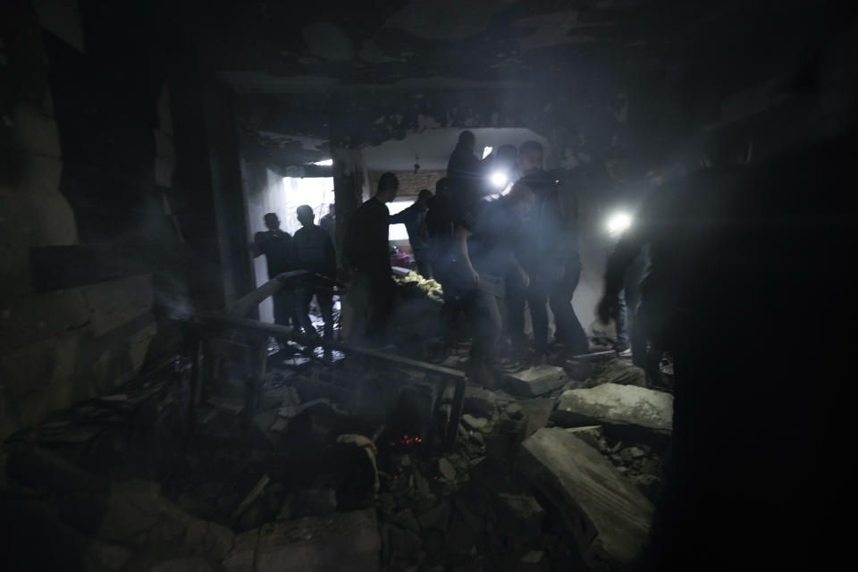 Palestinians inspect the site of a building damaged in an Israeli military raid in the West Bank city of Jenin, Tuesday, March 7, 2023. The raid led to a gunbattle that killed at least six Palestinians. Israeli officials said the target was a militant who killed two Israeli brothers in a West Bank shooting last week. The man was among those killed on Tuesday. (AP Photo/Majdi Mohammed)
