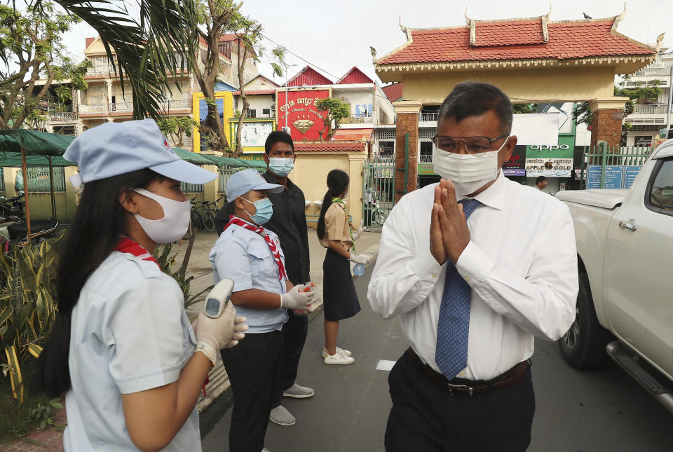 Cambodian Education Minister Hang Chuon Naron, right, greets students during his visit to Santhormok high school, in Phnom Penh, Cambodia, Monday, Nov. 2, 2020. Schools throughout Cambodia that had been shut in March because of the coronavirus crisis reopened Monday, but with limits on class sizes and hours.(AP Photo/Heng Sinith)