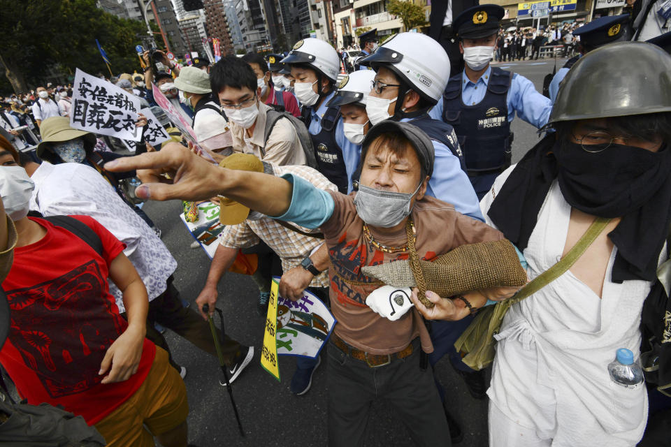 Police officers surround protesters against a state funeral for Japan's former Prime Minister Shinzo Abe, in Tokyo Tuesday, Sept. 27, 2022. A tense Japan prepared Tuesday for the rare and controversial state funeral for assassinated Abe, the longest-serving leader in his nation's modern history and one of the most divisive. (Minoru Iwasaki/Kyodo News via AP)