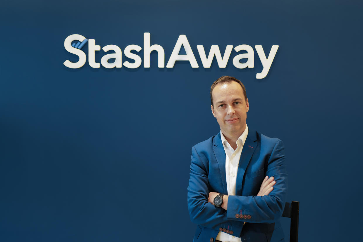 A man in blue suit – Michele Ferrario, co-founder and CEO of StashAway – standing with arms crossed under the StashAway logo.