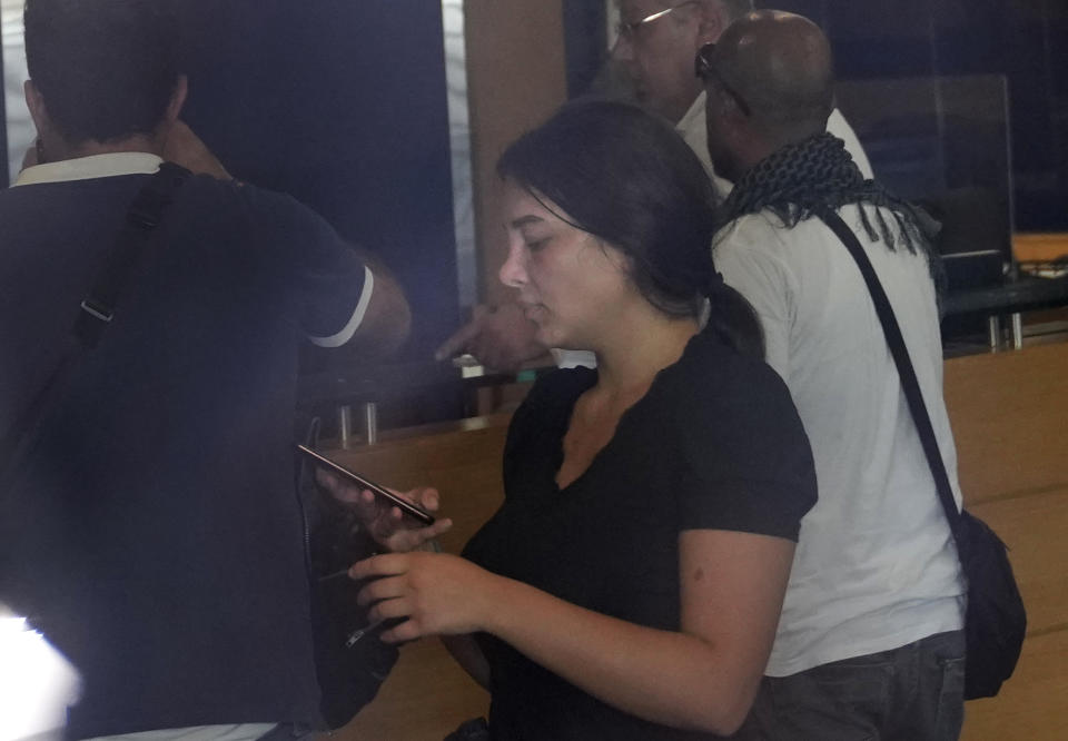 Lebanese Sali Hafez, center, accompanied by activists looks at her phone after breaking into a BLOM Bank branch brandishing what she later said was a toy pistol and taking $13,000 from her trapped savings accopunt, in Beirut, Lebanon, Wednesday, Sept. 14, 2022. Lebanon's cash-strapped banks have imposed strict limits on withdrawals of foreign currency since 2019, tying up the savings of millions of people. About three-quarters of the population has slipped into poverty as the tiny Mediterranean country's economy continues to spiral. (AP Photo/Hussein Malla)