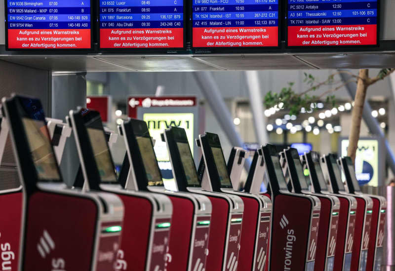 A notice board reads "Due to a warning strike, there may be delays in check-in" at one of 11 major German airports that have started a one-day strike. Oliver Berg/dpa