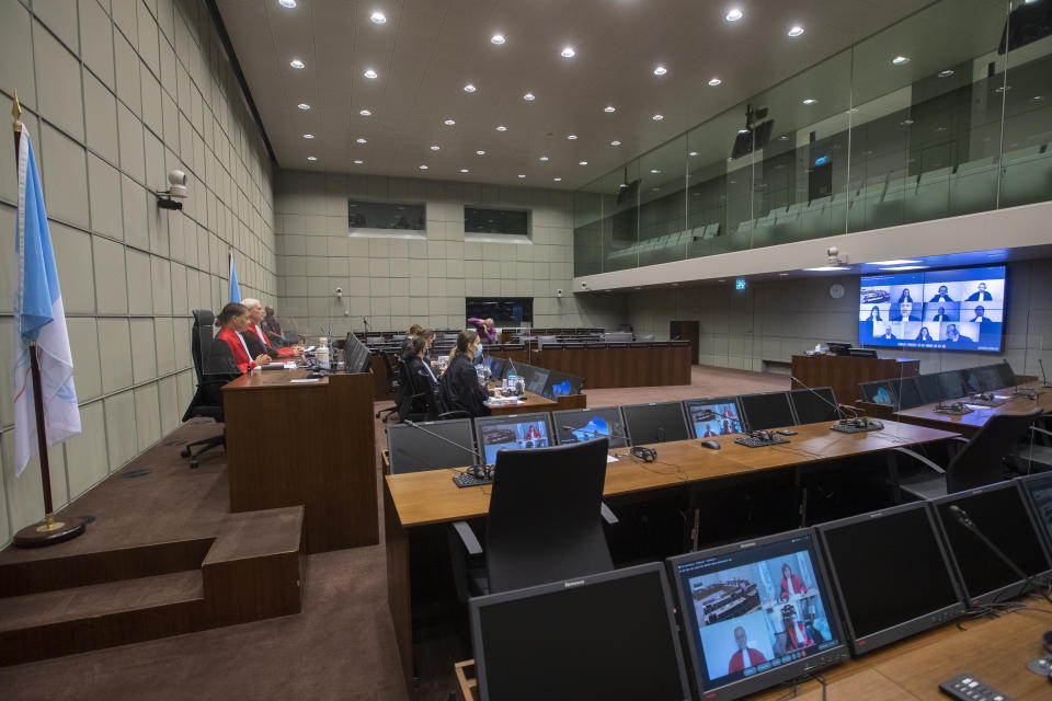 Presiding judge David Re, second left, and judge Janet Nosworthy, left, and the prosecution and defense counsel seen on screens via video link due to COVID-19 measures, open the session of the United Nations-backed Lebanon Tribunal where it is scheduled to hand down it's sentencing on Salim Jamil Ayyash, a member of the Hezbollah militant group who was convicted of involvement in the assassination of former Lebanese Prime Minister Rafik Hariri and 21 others 15 years ago, in Leidschendam, Netherlands, Friday Dec. 11, 2020. Ayyash is not in custody and is unlikely to serve any sentence. (AP Photo/Peter Dejong, Pool)