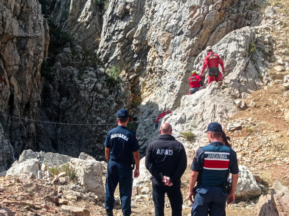 European Cave Rescue Association (ECRA) members and Turkish gendarmerie officers stand next to the entrance of Morca cave near Anamur, southern Turkey, Thursday, Sept. 7, 2023. Turkish and international cave rescue experts are working to save an American speleologist trapped at a depth of more than 1,000 meters (3,280 feet) in a cave in southern Turkey after he became ill. (Mithat Unal/Dia Images via AP)