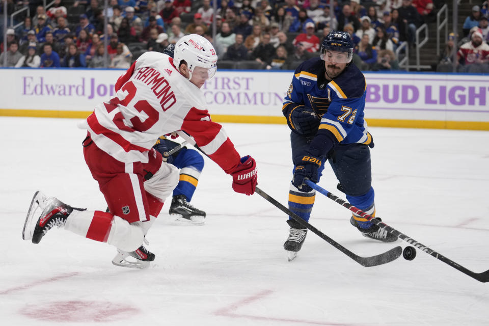 Detroit Red Wings' Lucas Raymond (23) shoots past St. Louis Blues' Justin Faulk (72) during the third period of an NHL hockey game Tuesday, Dec. 12, 2023, in St. Louis. (AP Photo/Jeff Roberson)