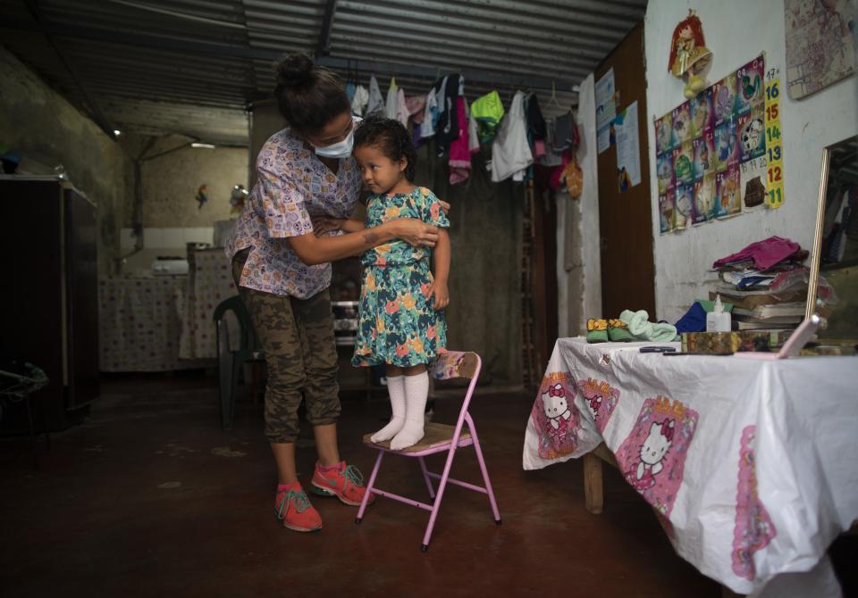 Elena Escalante helps her 3-year-old daughter Zaii prepare for a homespun beauty pageant in the Antimano neighborhood of Caracas, Venezuela, Friday, Feb. 5, 2021. Neighbors in the hillside barrio gathered for the carnival pageant tradition to select their child queen for the upcoming festivities. (AP Photo/Ariana Cubillos)