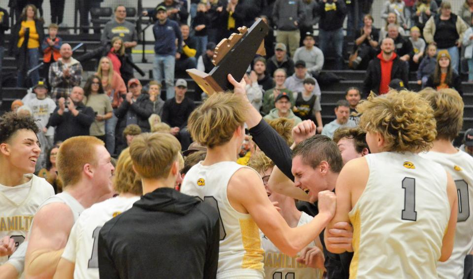 The Hamilton boys basketball team celebrates winning a district title on Friday.