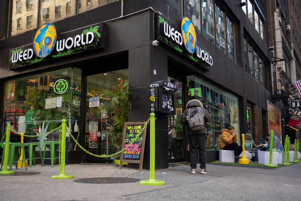 Outside a Weed World store, a patron in a yellow quilted jacket enjoys the merchandise.