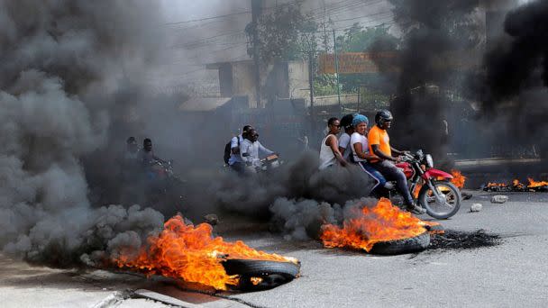 PHOTO: Motorcycle drivers pass through a burning road block as anger mounted over fuel shortages that have intensified as a result of gang violence, in Port-au-Prince, Haiti, July 13, 2022. (Ralph Tedy Erol/Reuters)