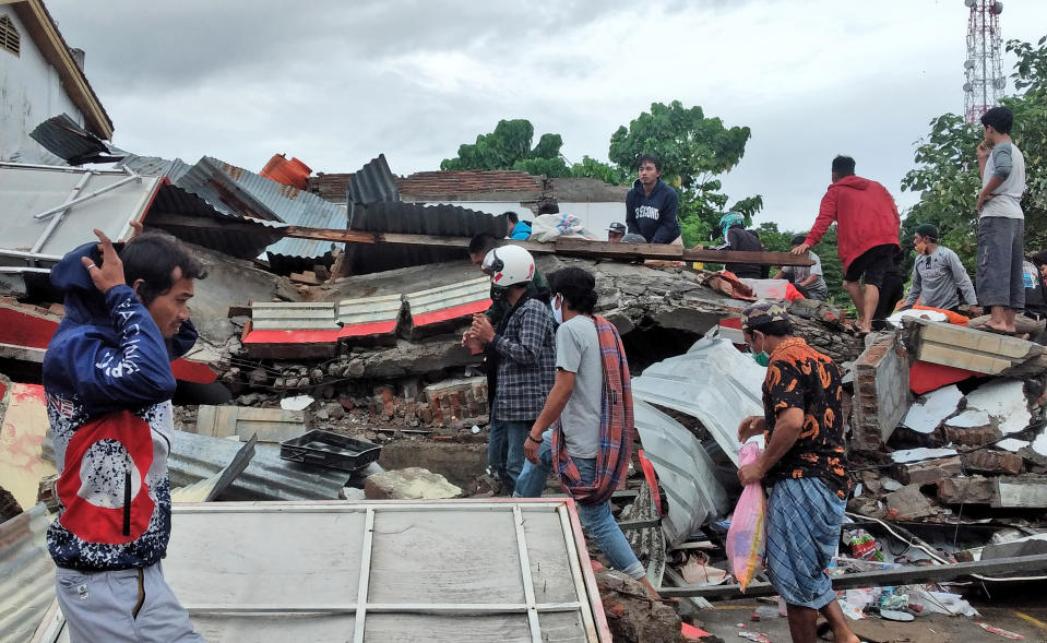 Residents inspect the ruin of a building damaged by an earthquake in Mamuju, West Sulawesi, Indonesia, Saturday, Jan. 16, 2021. Damaged roads and bridges, power blackouts and lack of heavy equipment on Saturday hampered Indonesia's rescuers after a strong and shallow earthquake left a number of people dead and injured on Sulawesi island. (AP Photo/Yusuf Wahil)